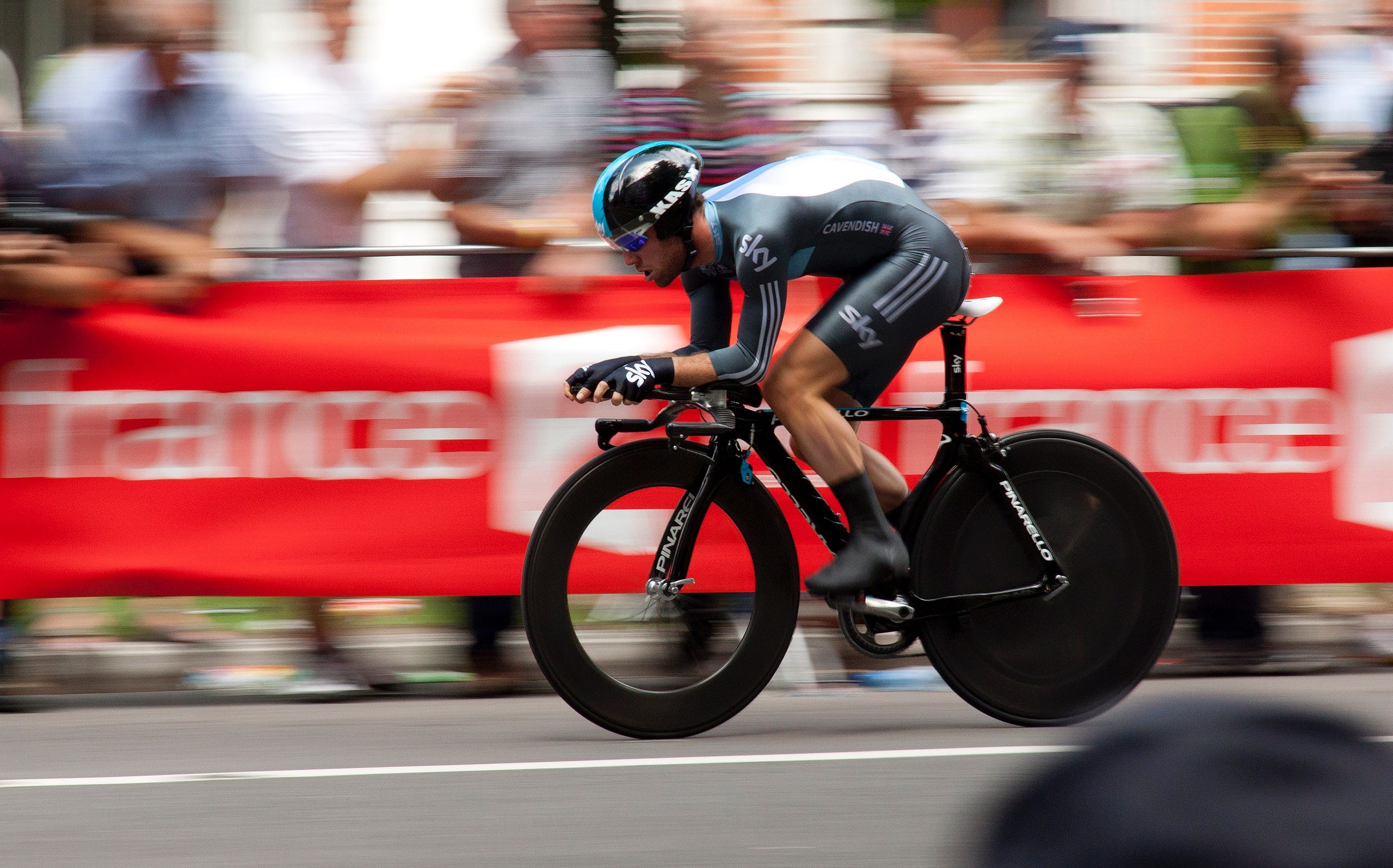 A cyclist riding a time trial bicycle sets off in a race.